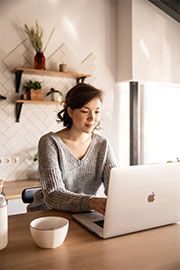 A woman works on a laptop at home.