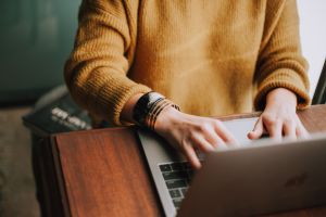 An image of a person in an orange sweater using a computer